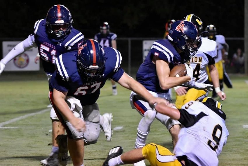 Leake Academy’s Levi Brown runs for some positive yards as Carter Walsworth (67) and Jarod Sims(51) block during an earlier game. The Rebels will visit undefeated Heritage Academy Friday night.